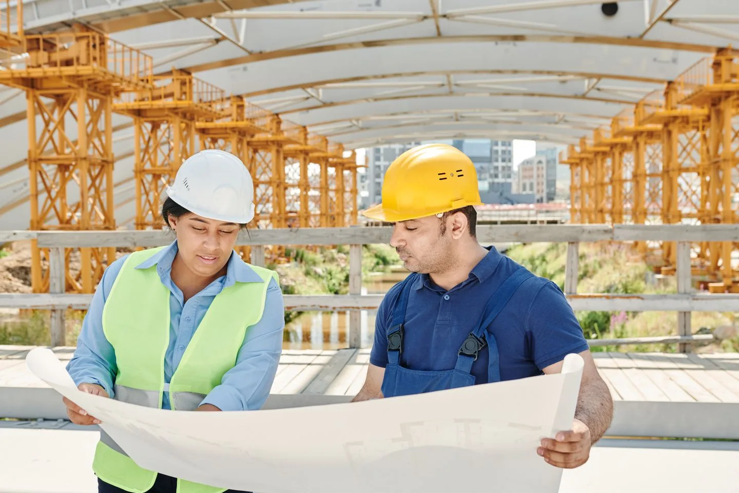 Deux professionnels du bâtiment étudient des plans sur un chantier