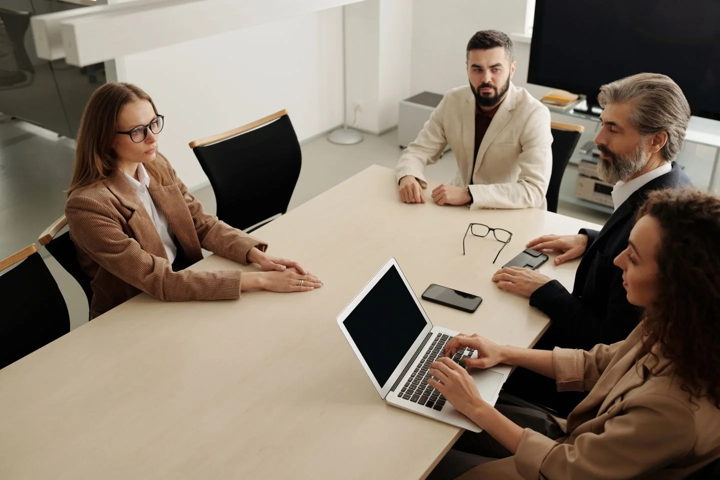 Une équipe échange autour d’une table avec un ordinateur et des documents